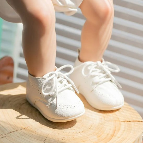 Bébé assis porte chaussure bebe blanc lacets