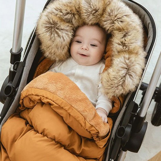 bébé souriant en poussette dans chancelière poussette brun doudou