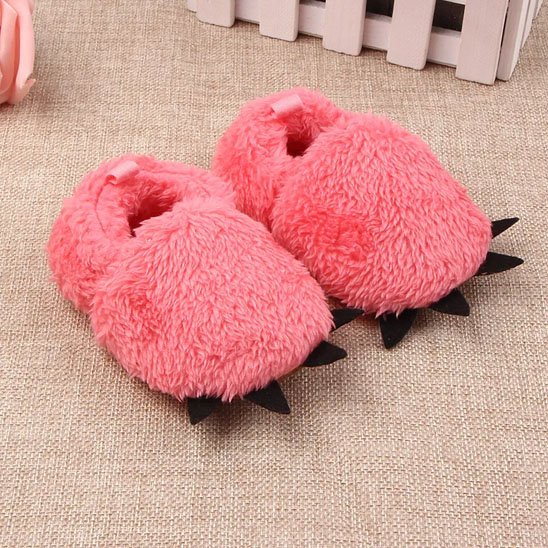 Chausson bébé rose foncé fourrure posé au sol