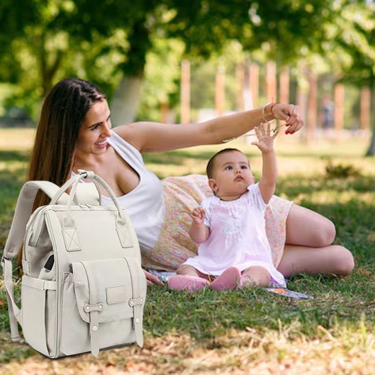 maman allongée dans gazon joue avec bébé sac à langer à côté