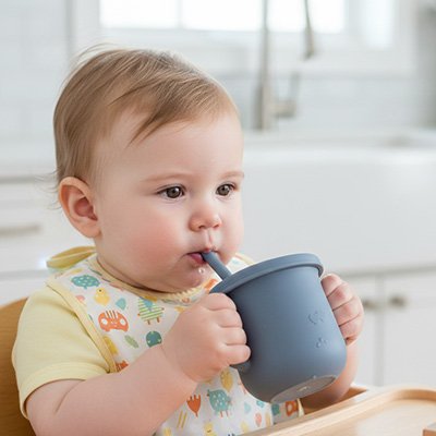 bébé à table boit dans un gobelet bebe bleu
