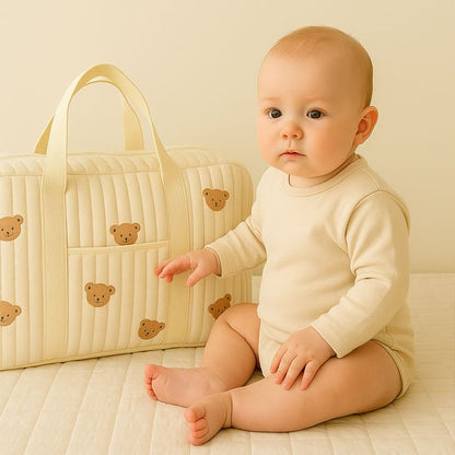 bébé assis près sac à langer beige ourson
