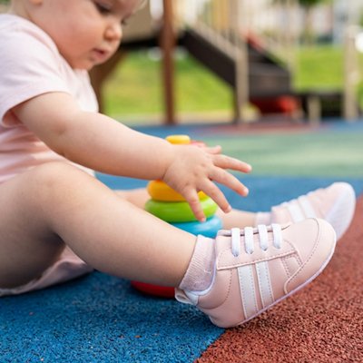 Bébé assit porte chaussure bebe rose au parc