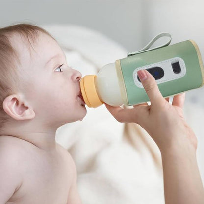 Bébé boit son biberon dans chauffe biberon vert
