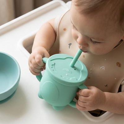 Bébé boit son jus dans gobelet bebe vert