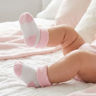bébé couché avec chaussette bébé rose blanc dans la chambre 