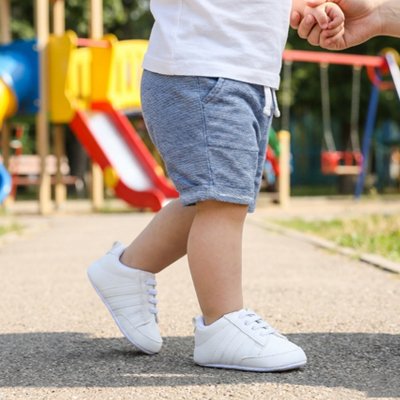 Bébé debout porte chaussure bebe blanc au parc