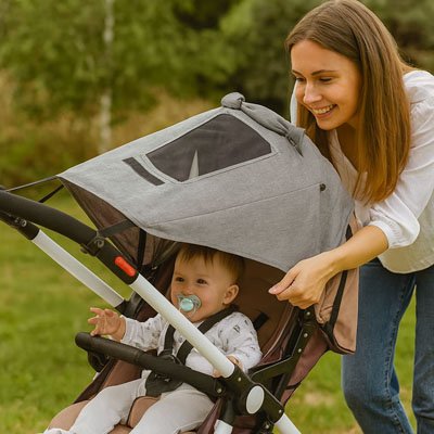 Bébé dehors avec maman sous parasol poussette​ gris