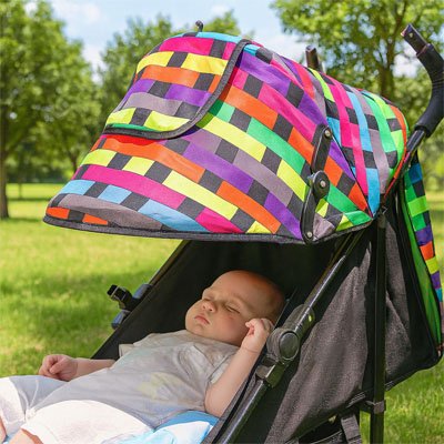 Bébé dehors sous par soleil pour poussette​ arc en ciel