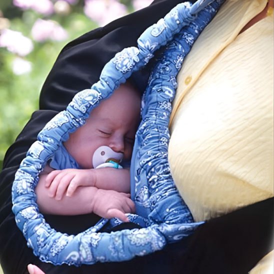 Bébé dort contre maman dans écharpe de portage bleu