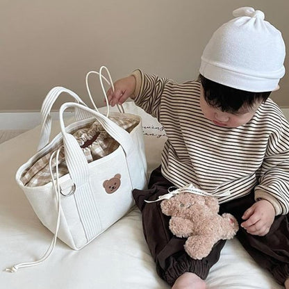 bébé joue avec doudou près sac à langer blanc doudou