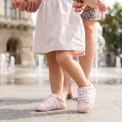 Bébé marchant porte chaussure bebe rose dans la rue