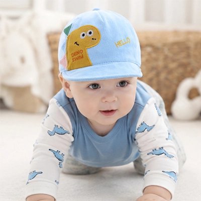 Bébé portant casquette bebe bleu dinosaure sur le lit