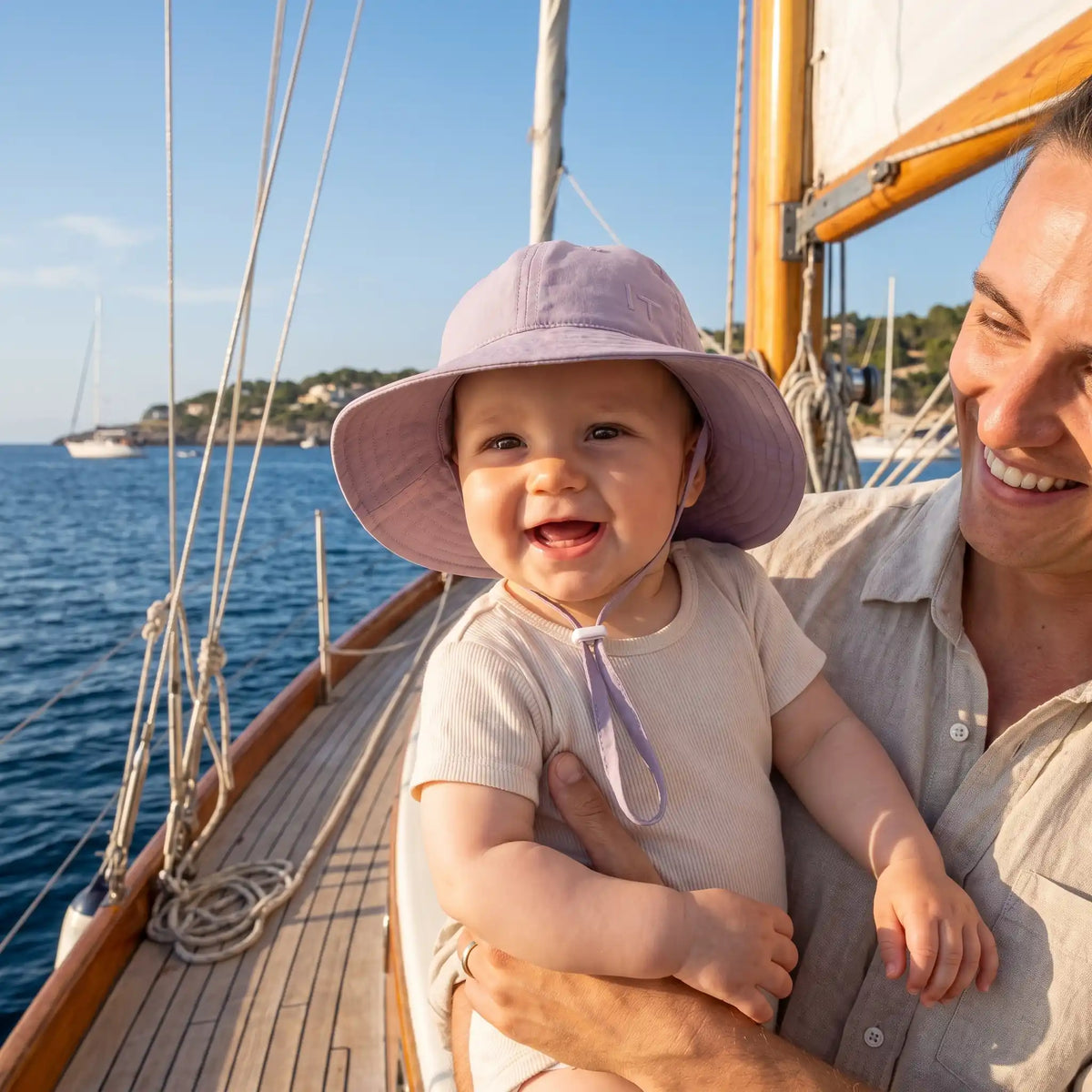 Bébé portant chapeau bebe violet en bateau avec papa