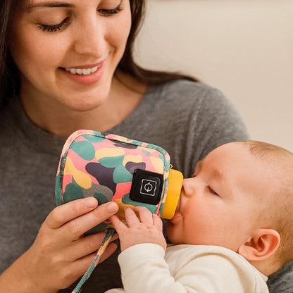 Bébé prend  son biberon dans chauffe portable biberon bicolore