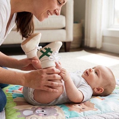 Bébé riant avec maman porte chaussure bebe blanc vert