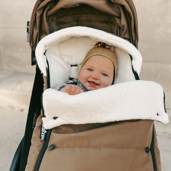 Bébé souriant dans chancelière poussette marron blanc