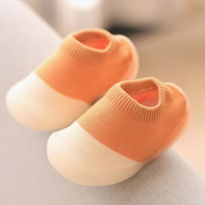 Chaussure pour bebe orange blanc gaine posé sur table