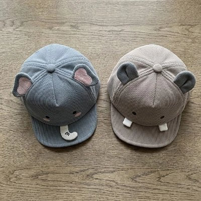 Deux casquettes bebe bleu éléphant et gris ours sur table