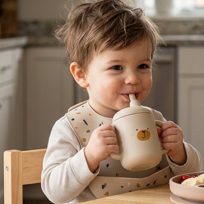 Enfant à table buvant dans son gobelet bebe beige