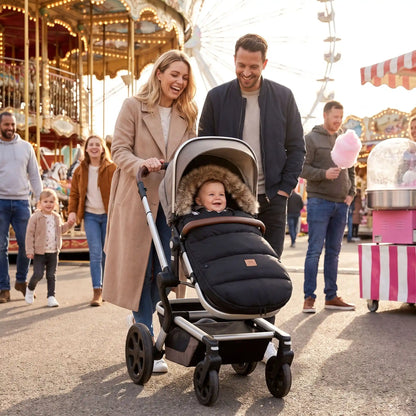 Famille à fête foraine avec bébé dans chancelière poussette noir