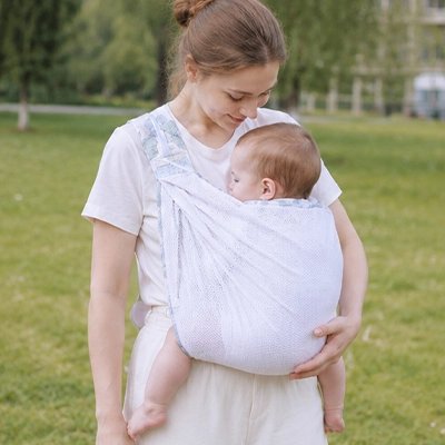 Maman à extérieur avec bébé dans écharpe de portage blanc