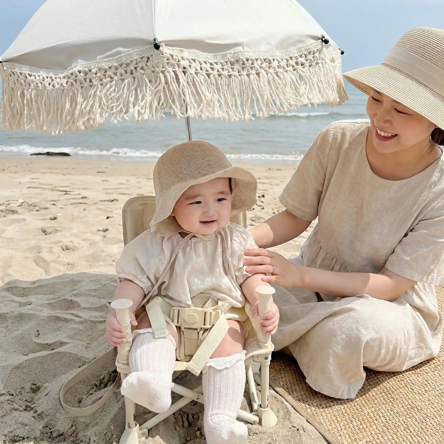 maman à plage avec bébé sous ombrelle pour poussette beige