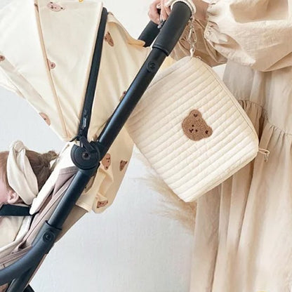 Maman accroche trousse de toilette bebe ourson sur poussette