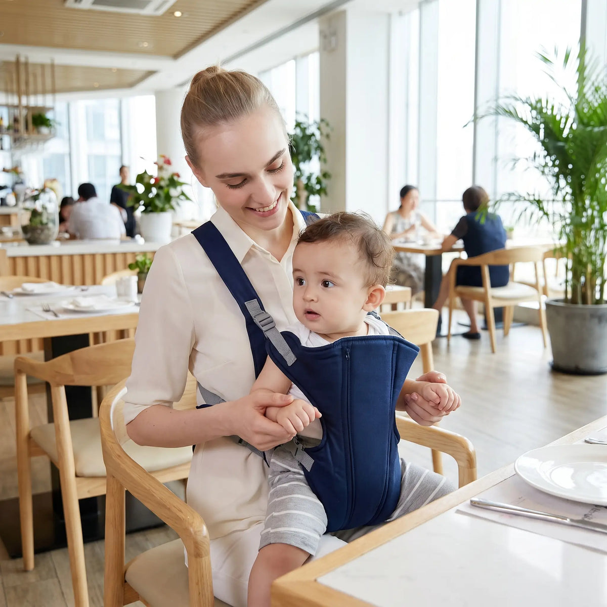 Maman au restaurant avec bébé dans porte bebe bleu