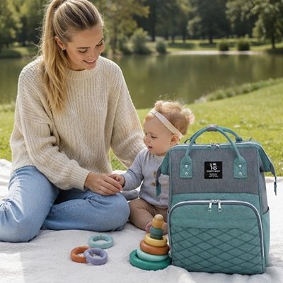 Maman et bébé au parc avec sac a langer vert gris