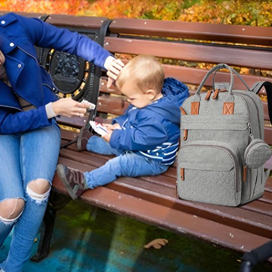 maman bébé sur banc au parc avec sac à langer