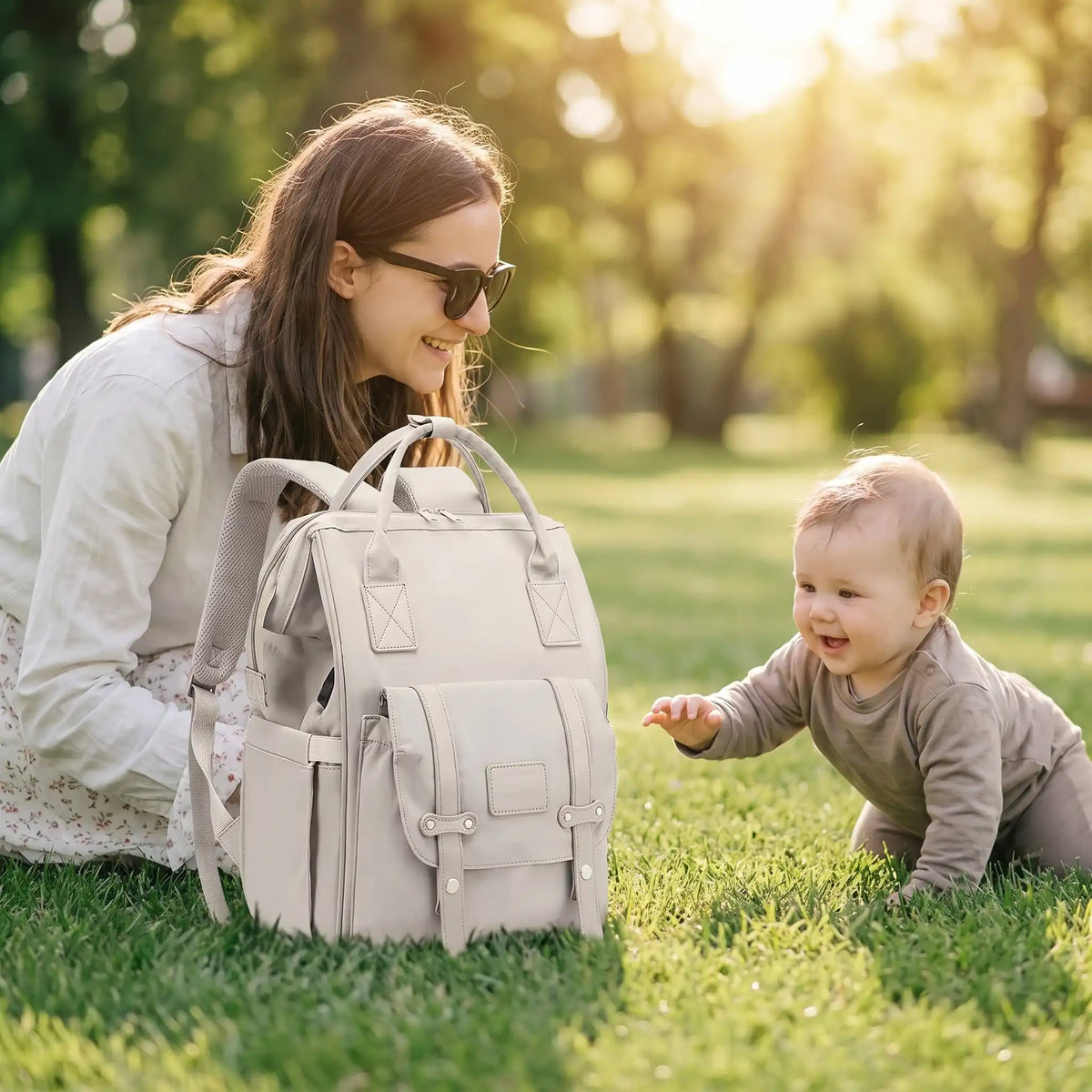 Maman bébé sur gazon avec sac a langer blanc