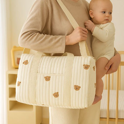 maman debout tient bébé avec sac à langer beige ourson à épaule