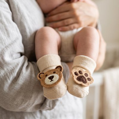 Maman debout tient bébé portant chaussettes brun ours