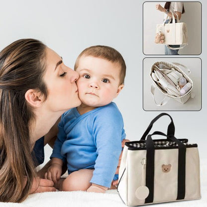 maman fait bisou bébé près sac à langer blanc doudou