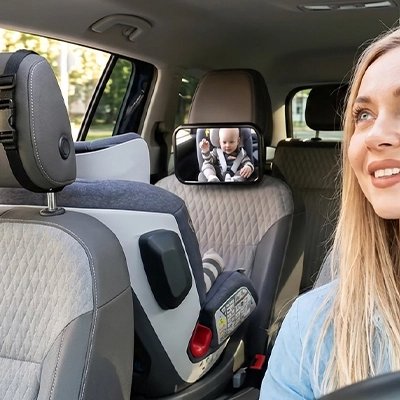 Maman souriante au volant regarde dans miroir voiture bébé