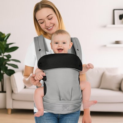 maman souriante tient bébé contre elle dans porte bébé gris