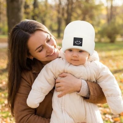 Maman  tient bébé portant bonnet bebe blanc mignon au parc