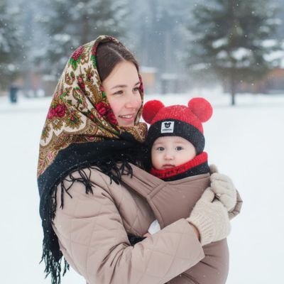 Maman tient bébé portant bonnet bebe noir rouge à extérieur