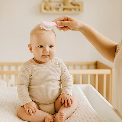 Maman utilise brosse de  trousse de toilette bebe