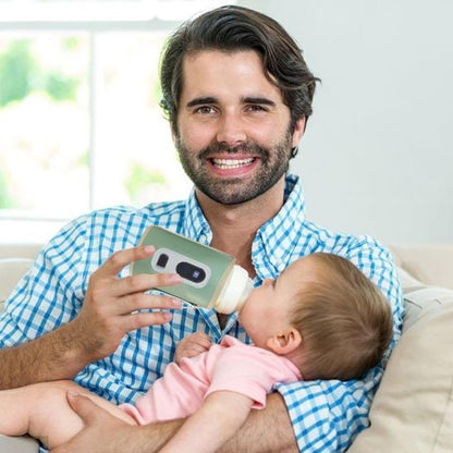 Papa donne biberon à bébé dans chauffe biberon vert