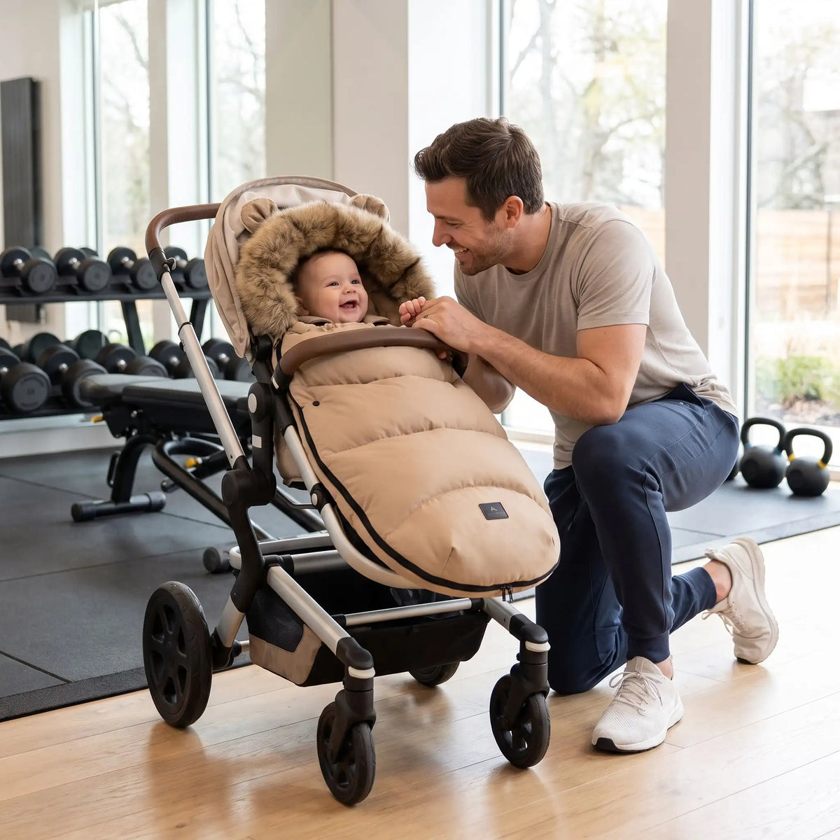 Papa en salle sport avec bébé dans chancelière poussette brun