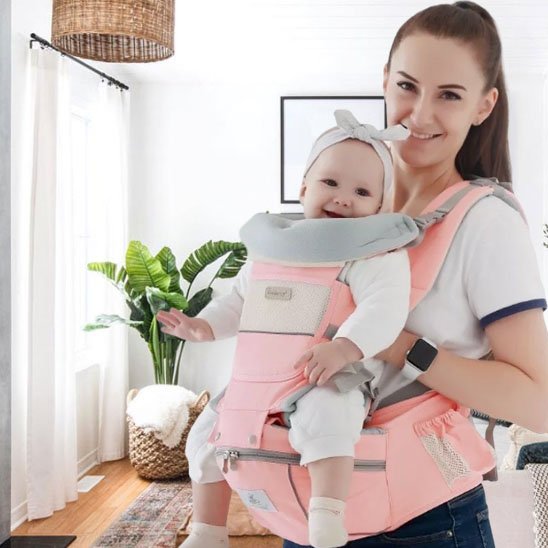 Porte bebe  maman-portant-bébé-en-avant-dans-porte-bébé-rose-dans-le-salon