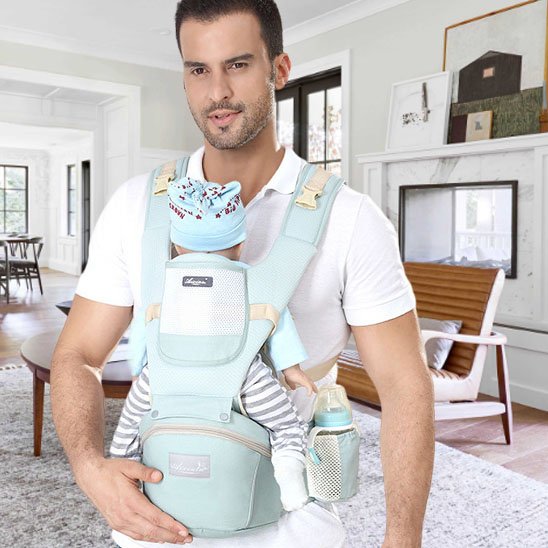 Porte bebe  Papa-portant-bébé-en-avant-dans-porte-bébé-vert-dans-le-salon