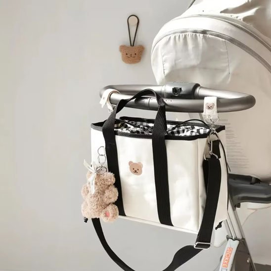 sac à langer blanc doudou accroché à poussette blanche
