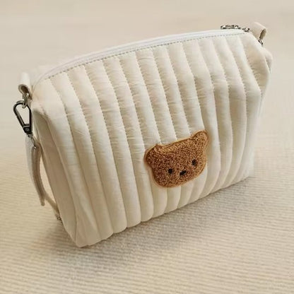 Trousse de toilette bebe fermée et  posée sur lit